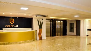 A reception area with a reception desk, a potted plant, an elevator, and a wall-mounted air conditioning unit. - Gold Flat  (João Pessoa)
