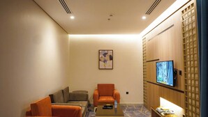 A hotel room with a sofa, armchairs, a small table, a TV, and a patterned carpet. - Seagull Apartment Service (Jeddah)