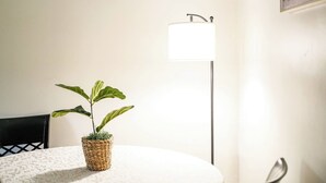 Une pièce avec une table ronde, une plante en pot, un lampadaire et une chaise.
