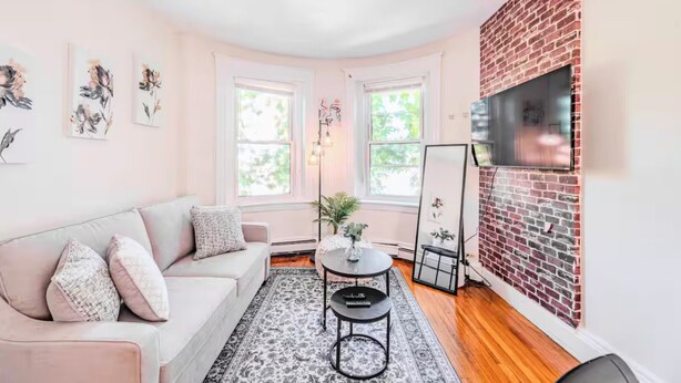 Un salon chaleureux avec un canapé, une petite table et un mur décoratif en briques.