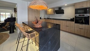 Une cuisine moderne dotée d’un îlot central, de meubles en bois et d’un four encastré.