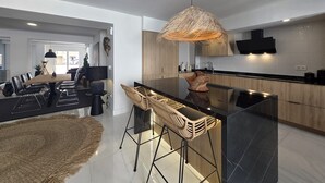 Une cuisine moderne dotée d’un îlot central, de tabourets de bar et d’un luminaire suspendu.
