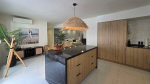 Une cuisine moderne dotée d’un îlot central, de meubles en bois et d’un luminaire suspendu.