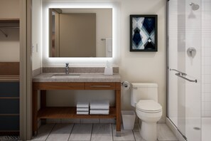A modern bathroom with a wooden vanity, a large mirror, a toilet, and a glass shower enclosure. - Candlewood Suites Mankato East By Ihg (Mankato)
