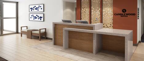 A reception desk with two chairs, a large window, and a wall with geometric patterns and a logo.