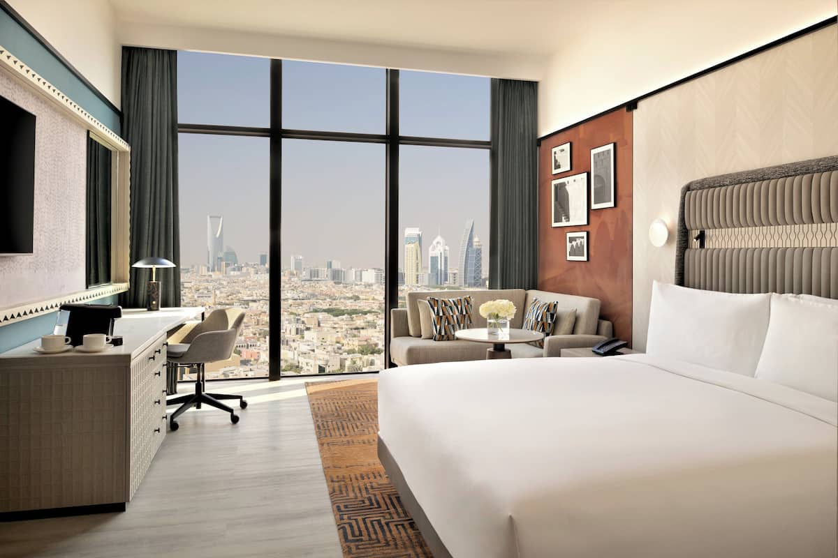 Habitación de hotel con una cama grande, un escritorio, un sofá y vistas a la ciudad.