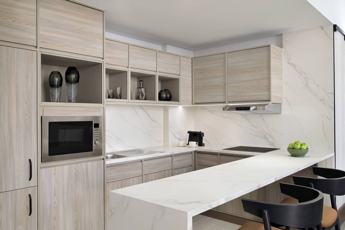 Una cocina moderna con electrodomésticos integrados, encimera de mármol y una isla grande con taburetes de bar.