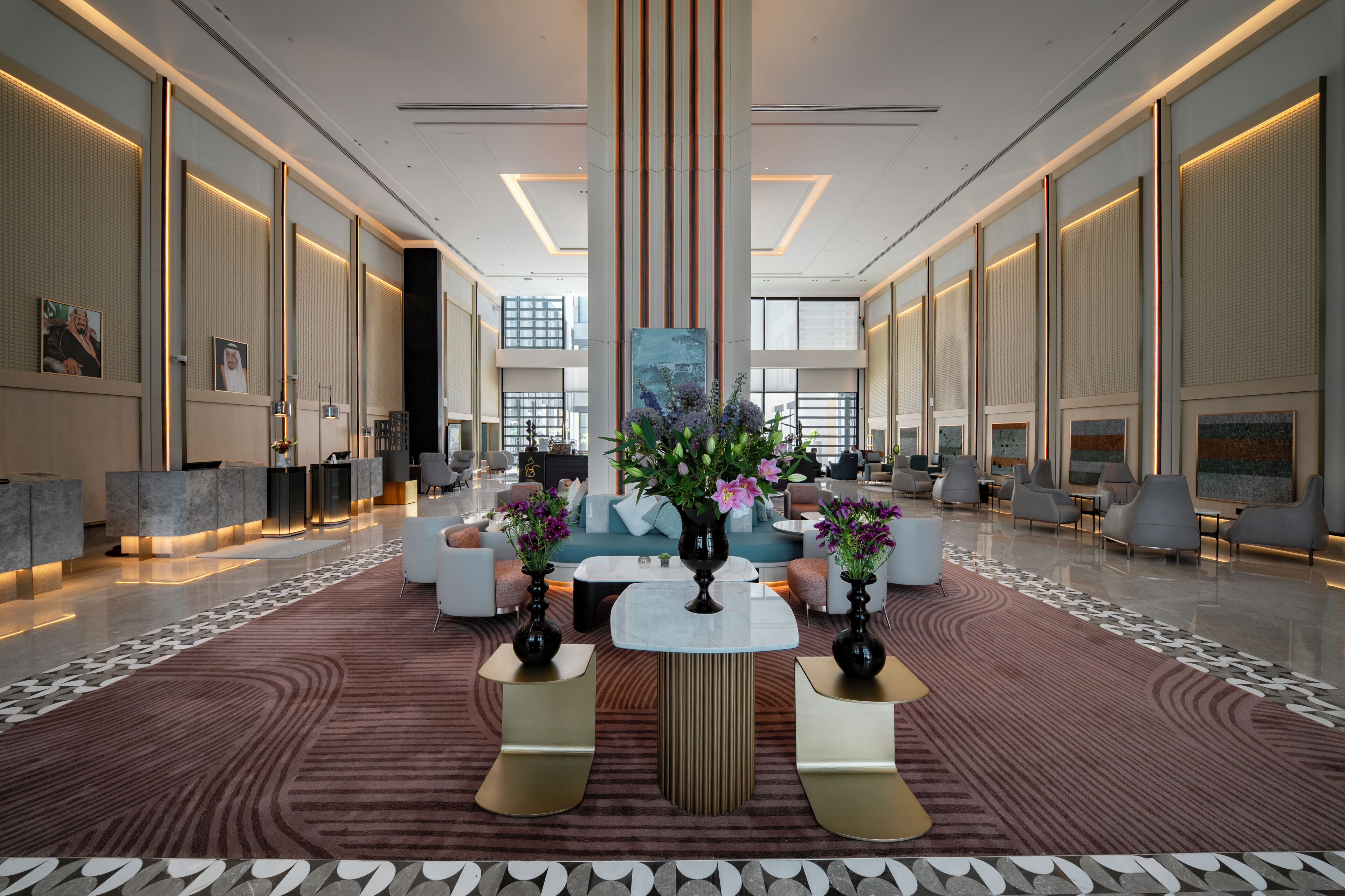 A spacious lobby with a central seating area, a reception desk, and a large window providing natural light.