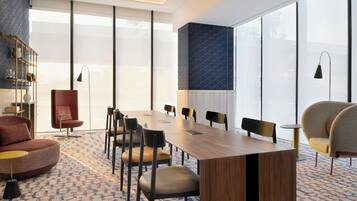 A modern conference room with a long table, comfortable chairs, a sofa, and a patterned carpet.