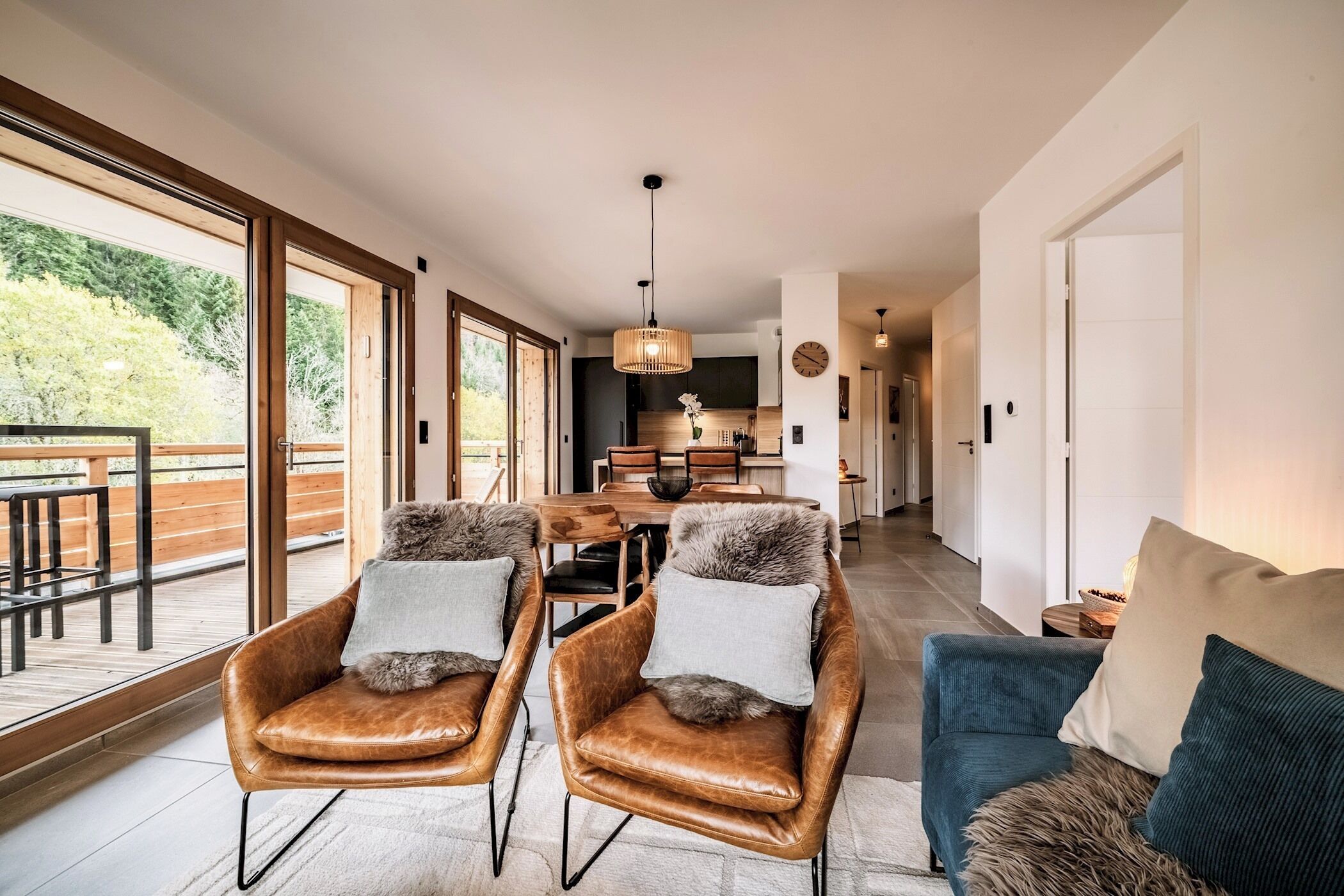 Een ruime woonkamer met leren fauteuils, een bank en een eettafel.