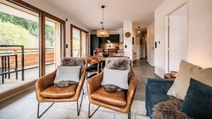 A spacious living area with leather armchairs, a sofa, and a dining table. - Mimosa–Apartment near piste, mountain-view balcony (Les Gets)
