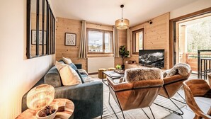 A cozy living room with a sofa, chairs, a coffee table, and a TV. - Mimosa–Apartment near piste, mountain-view balcony (Les Gets)