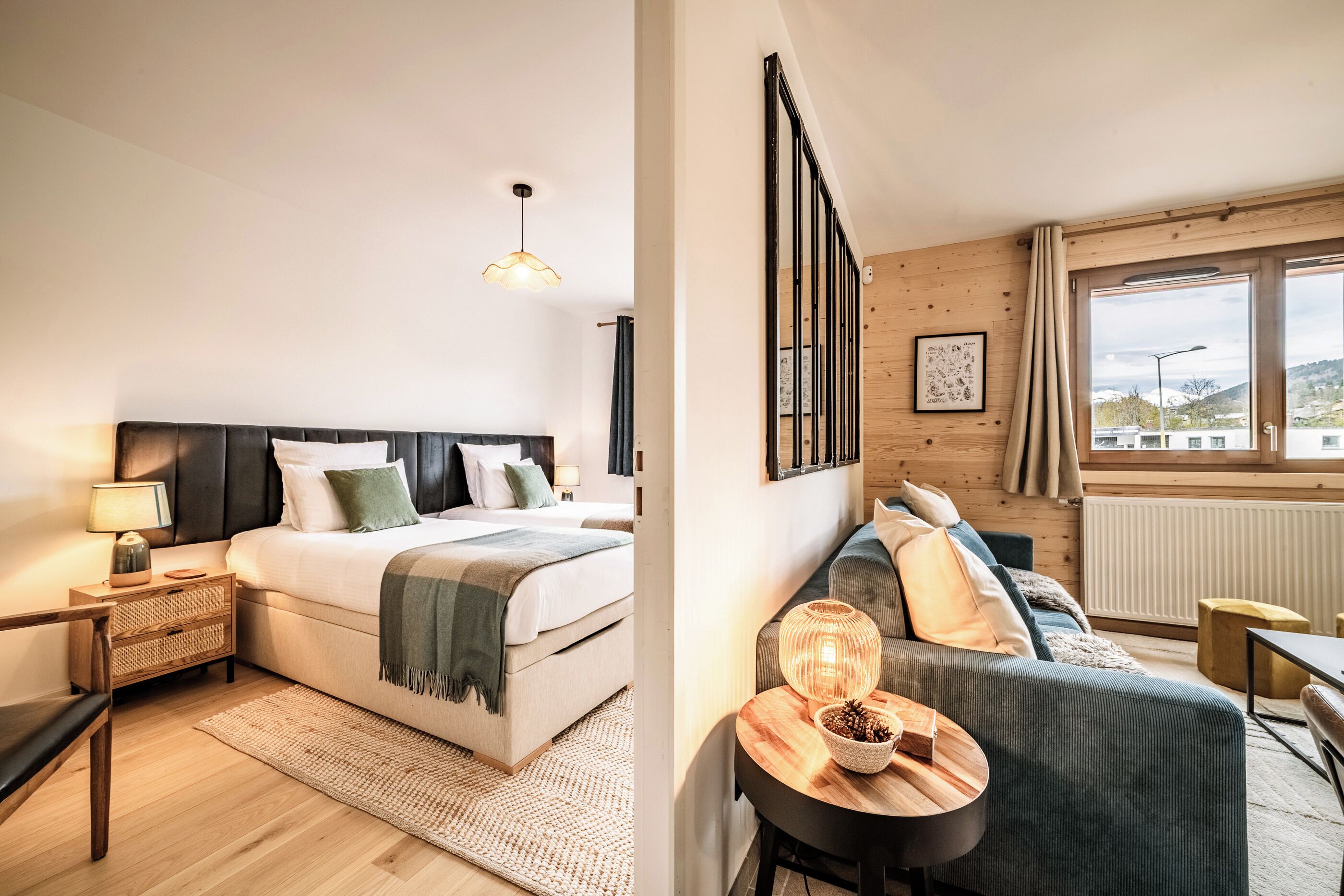 Een moderne hotelkamer met een groot bed, een zithoek met een bank en een tafel, en uitzicht buiten door een groot raam.