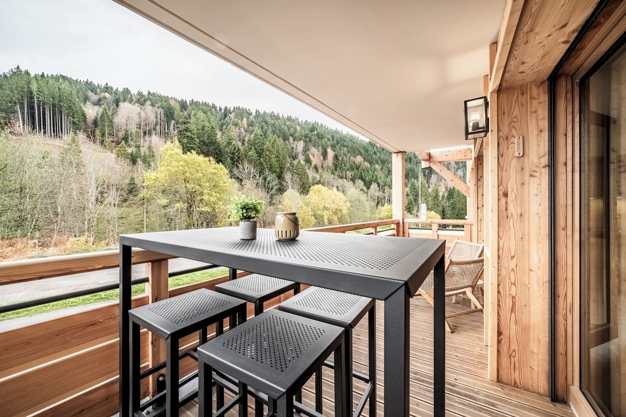 Une terrasse en bois avec une table et des chaises, donnant sur une colline boisée.