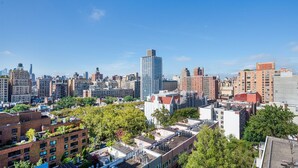 Un paisaje urbano con edificios de diferentes tipos, incluyendo rascacielos y construcciones más pequeñas, bajo un cielo azul despejado.