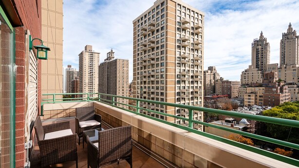 A balcony with wicker furniture and a view of high-rise buildings. - Contemporary 2 Bed 2 Bath Apt Bright and Sunny (New York)