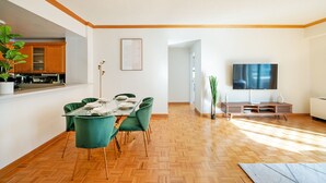 A modern living room with a dining area, wooden flooring, and a flat-screen TV. - Contemporary 2 Bed 2 Bath Apt Bright and Sunny (New York)