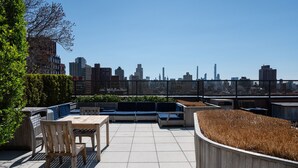 A rooftop patio with a seating area, a table, and a view of a city skyline. - Stunning Apartment for 4 2 Bedrooms 2 Bath (New York)