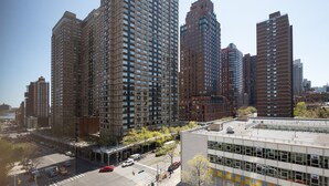 A high-rise urban area with multiple tall buildings, a clear sky, and a busy intersection with cars and a yellow bus. - Stunning Apartment for 4 2 Bedrooms 2 Bath (New York)