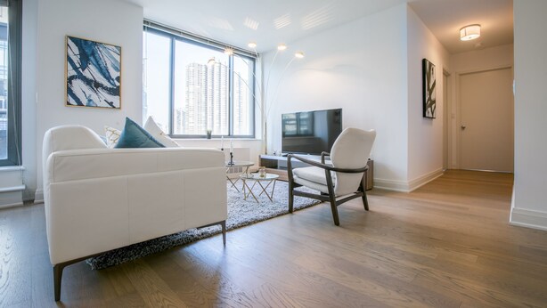 A modern living room with a white sofa, a coffee table, and a TV. - Bright 2 Bedrooms 2 Bathrooms Unit With Balcony (New York)