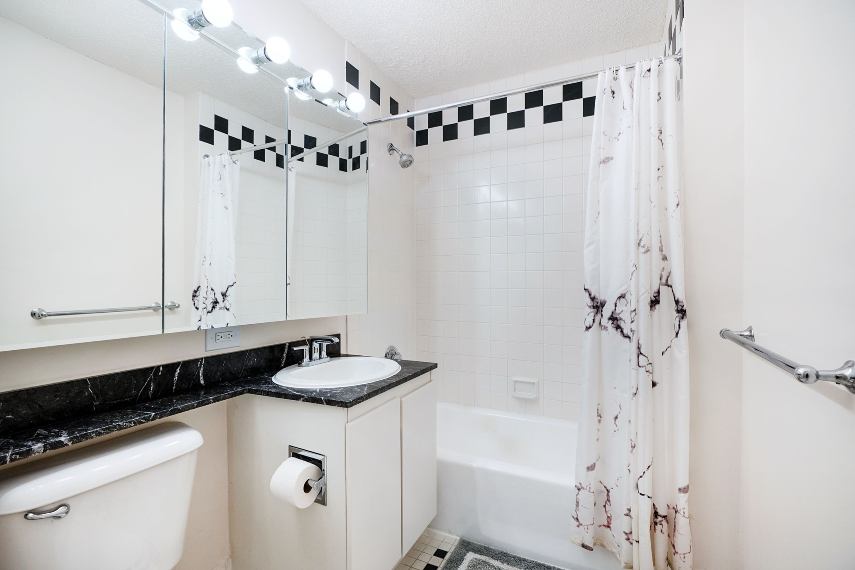 Une salle de bain avec un lavabo blanc, des toilettes, une baignoire et un rideau de douche.