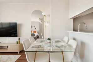 A modern dining area with a glass table, white chairs, and a minimalist decor. - Gorgeous Studio Apartment (New York)