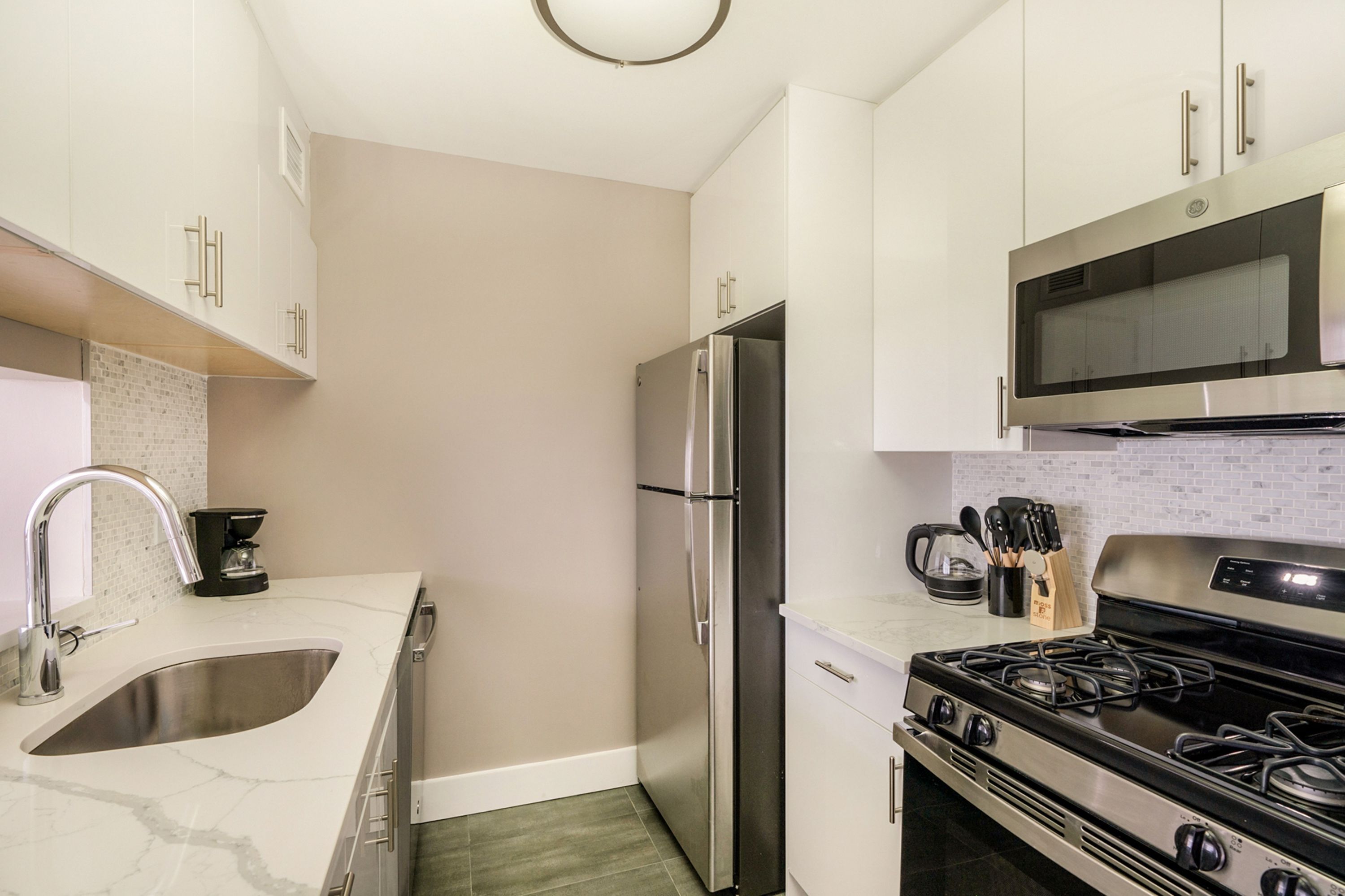 A modern kitchen with a stainless steel refrigerator, a built-in microwave, and a gas stove.