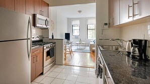 A modern kitchen with wooden cabinets, stainless steel appliances, and a dining area with a wooden table and chairs. - Prime Upper West Side Location 1 Bedroom Apt (New York)