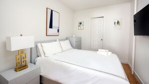 A neatly arranged bedroom with a bed, bedside tables, a lamp, and artwork on the walls. - Prime Upper West Side Location 1 Bedroom Apt (New York)