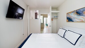 Une chambre d’hôtel avec un grand lit, un téléviseur à écran plat fixé au mur et un tableau accroché au mur.