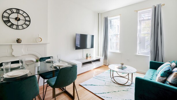 Un salon moderne comprenant un coin repas, un téléviseur à écran plat et une grande horloge murale.