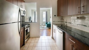 Une cuisine moderne dotée d’appareils électroménagers en acier inoxydable, de meubles en bois et d’un revêtement mural en carreaux.
