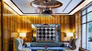 A lobby with a plush sofa, two armchairs, a coffee table, and a modern chandelier. - Fully Furnished Studio Apartment (New York)