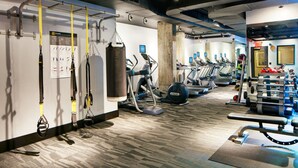 A gym with exercise equipment, including treadmills, ellipticals, and a punching bag. - Fully Furnished Studio Apartment (New York)