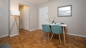 A dining area with a table set for two, a floor lamp, and a mirror on the wall. - 2 Bed Apt Ideally Located in UES of Manhattan (New York)