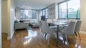 Een moderne woonkamer met een eethoek, grote ramen en uitzicht op de stad.