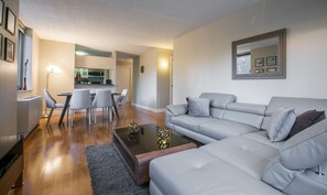 Una sala de estar moderna con un sofá gris, una mesa de centro y un comedor con sillas y una mesa.