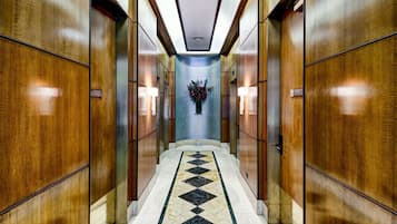 A hallway with wooden paneling, a marble-tiled floor, and a central floral arrangement.