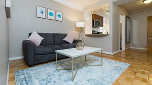 Un salon moderne avec un canapé gris, une table basse blanche et un tapis à motifs bleus.