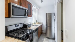 Une cuisine moderne dotée d’appareils électroménagers en acier inoxydable, d’armoires en bois et d’un plan de travail en granit.