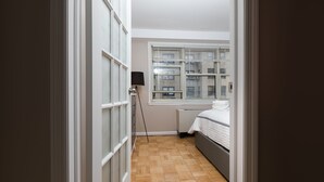 Une petite pièce avec un lit, une fenêtre munie de stores et un radiateur.