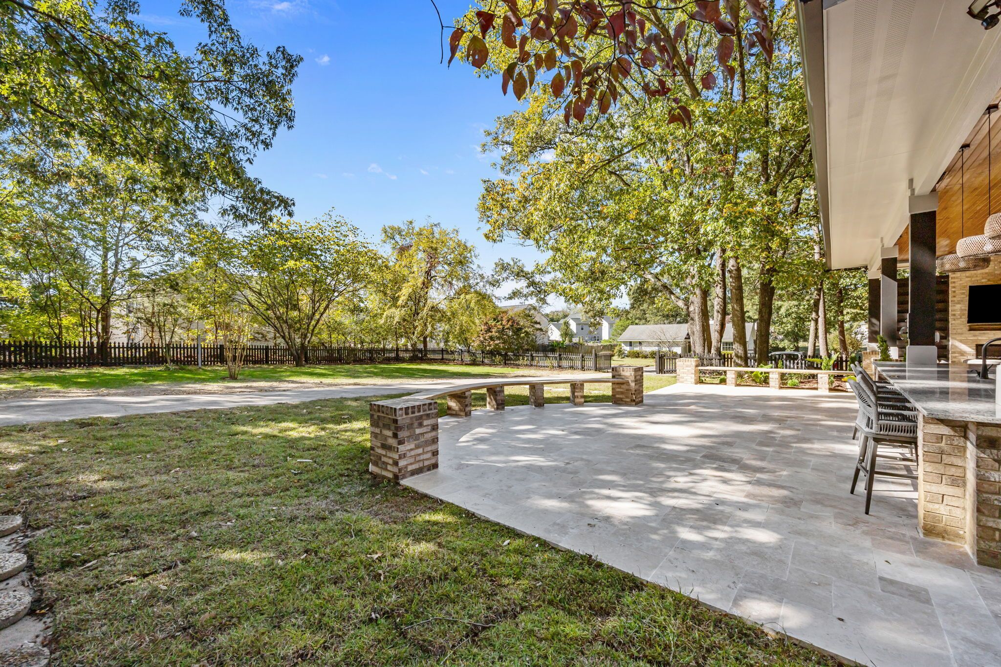 An outdoor patio area with a stone floor, a wooden bench, and a brick planter.