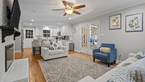 A modern living room with a sofa, a blue armchair, and a patterned rug. - The Retreat at Kincaid (Raleigh)
