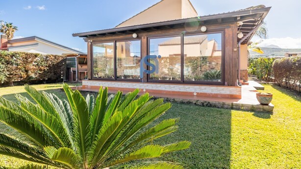 A modern house with large glass windows, a well-maintained lawn, and a stone pathway leading to the entrance. - The garden of Seba, a splendid detached villa surrounded by greenery (Piana Calzata)