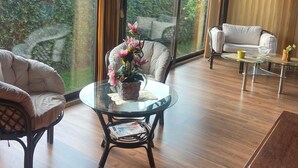 A spacious room with a glass table, two chairs, a sofa, and a wooden floor. - The garden of Seba, a splendid detached villa surrounded by greenery (Piana Calzata)