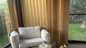A modern room with a glass coffee table, a beige sofa, and a view of greenery outside. - The garden of Seba, a splendid detached villa surrounded by greenery (Piana Calzata)