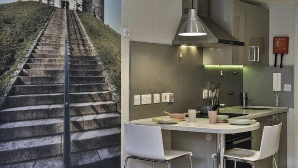 A modern kitchen with a dining area, a staircase leading to a historic building, and a view of the surrounding landscape. - Student Only Samuel Tuke (York)