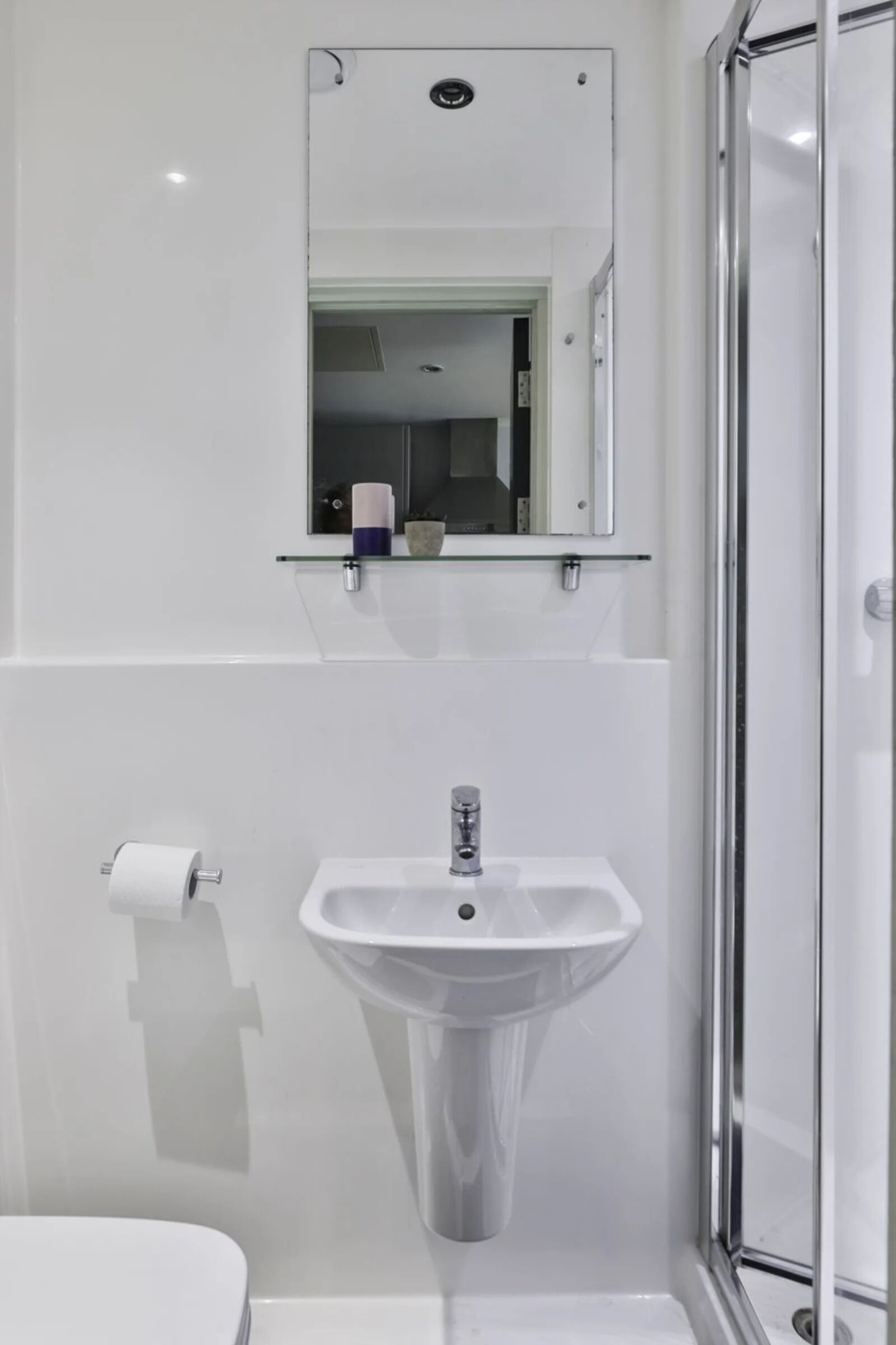 A modern bathroom with a white sink, a toilet, and a glass shower enclosure.