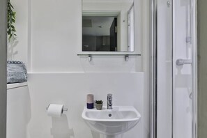 A bathroom with a white sink, a mirror, and a toilet paper holder. - Student Only Samuel Tuke (York)