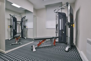 A gym with mirrored walls, a bench press, and a squat rack. - Student Only Samuel Tuke (York)